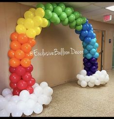 an arch made out of balloons in the shape of a rainbow is on display at this school hallway