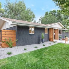 a small gray house in the middle of a yard