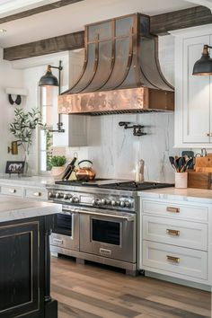 a kitchen with white cabinets and stainless steel range hood over an island in the middle