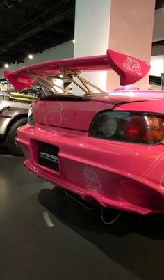 the back end of a pink car on display