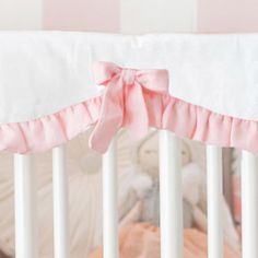 a baby crib with a pink bow on it's bed rail and bumper