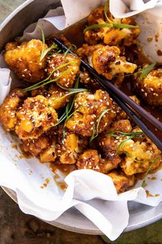 a bowl filled with fried food and chopsticks