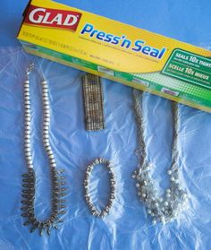 three necklaces and two bracelets on a blue sheeted surface with a box of glad presh seal