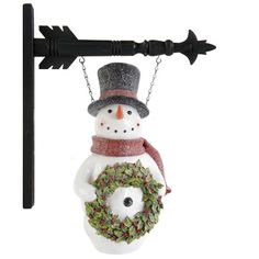 a snowman ornament hanging from a hook on a pole with a wreath