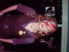 a woman with red eye patches on her face posing in front of a window at night