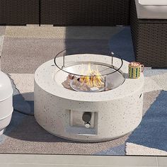 a fire pit sitting on top of a patio next to a white couch and chair