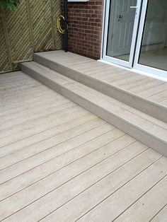 a wooden deck with steps leading up to the front door and patio doors on either side