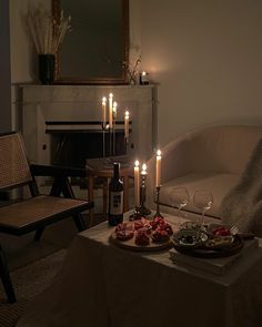 a living room with candles and food on the coffee table in front of the fireplace