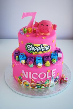 a pink birthday cake decorated with toys and numbers