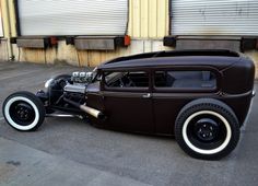 an antique car is parked in front of some garage doors