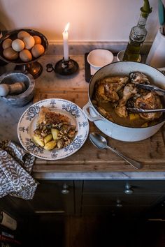 a wooden table topped with plates and bowls filled with food next to an open candle