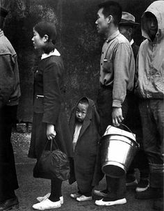 a group of people standing next to each other with buckets on their heads and one person holding a bag