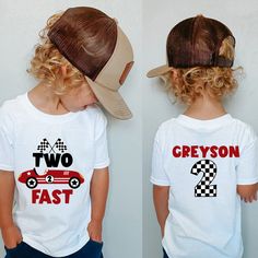 two children wearing matching t - shirts with hats on their heads and one child's hat in the shape of a car