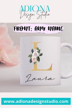 a white coffee mug with the letter l on it and flowers in front of it