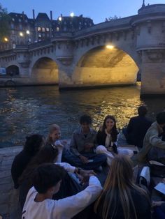 people sitting on the side of a river at night