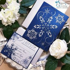 a blue and white wedding card on top of a silver plate next to some flowers