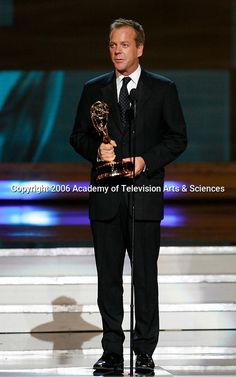 a man in a tuxedo holding an award for outstanding television arts and science