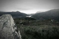 a view of mountains and water from the top of a hill in black and white