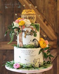 a winnie the pooh birthday cake is decorated with flowers and greenery on top