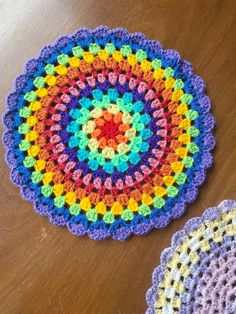 two crocheted coasters sitting on top of a wooden table