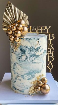 a white and blue marble cake with gold decorations