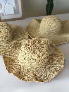 three straw hats sitting on top of a bed