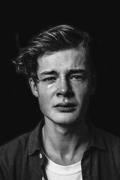 black and white photograph of a young man with tears on his face, looking at the camera