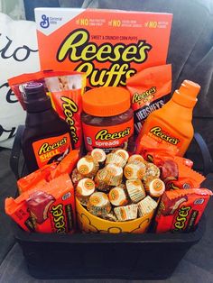 a basket filled with snacks and condiments sitting on a couch next to a bag of reese's stuff