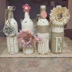 three wine bottles are decorated with flowers and burlap twine to spell out the word love