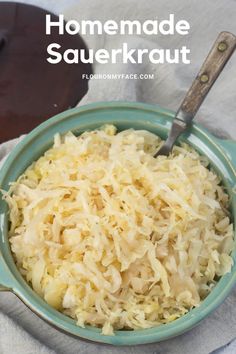 a bowl filled with sauerkraut on top of a white cloth next to a wooden spoon