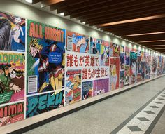 a long wall covered in comic books and advertisements on it's sides, along with an escalator