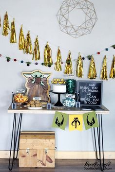 a baby yoda party with gold foil tassels and decorations on the wall