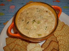 a bowl of dip surrounded by crackers on a plate