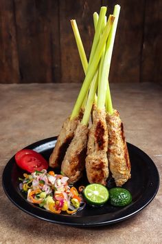 a black plate topped with meat and veggies