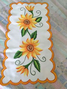 a white and orange quilt with sunflowers painted on it