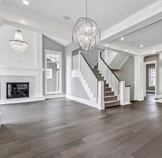 an empty living room with wood floors and chandelier