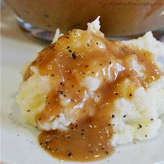 a white plate topped with mashed potatoes covered in gravy and caramel sauce