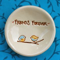 two little birds sitting on a branch with the words friends forever painted on it's side