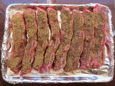 steak on tin foil with seasoning and pepper sprinkled over the top, ready to be cooked