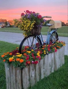 a bicycle with flowers in the basket is parked on a wooden fence near some grass