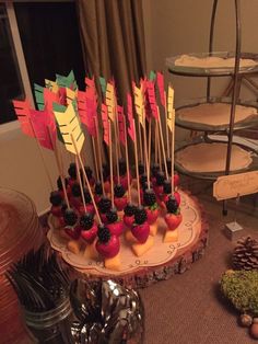 there is a cake with fruit on it and flags in the shape of arrows sitting on a plate