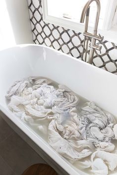 a white bath tub filled with water next to a window