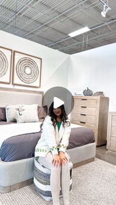 a woman sitting on top of a mattress in a bedroom next to a dresser and bed