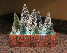 a wooden box filled with christmas trees on top of a counter