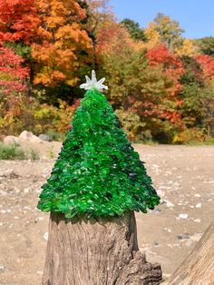 a glass christmas tree sitting on top of a wooden stump