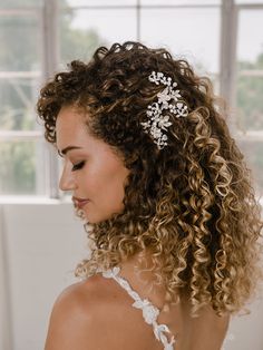 a woman with curly hair wearing a white dress and a headpiece in her hair