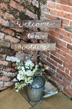 a sign that says welcome to our wedding next to a watering can with flowers in it