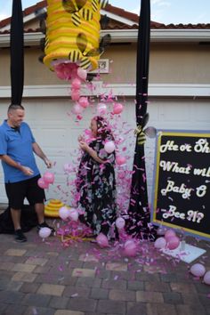 a man and woman standing next to each other in front of a building with balloons