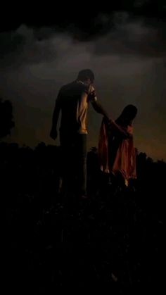 two people standing in the dark holding hands