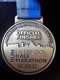 an award medal is displayed on a blue and white ribbon with the words liverpool marathon